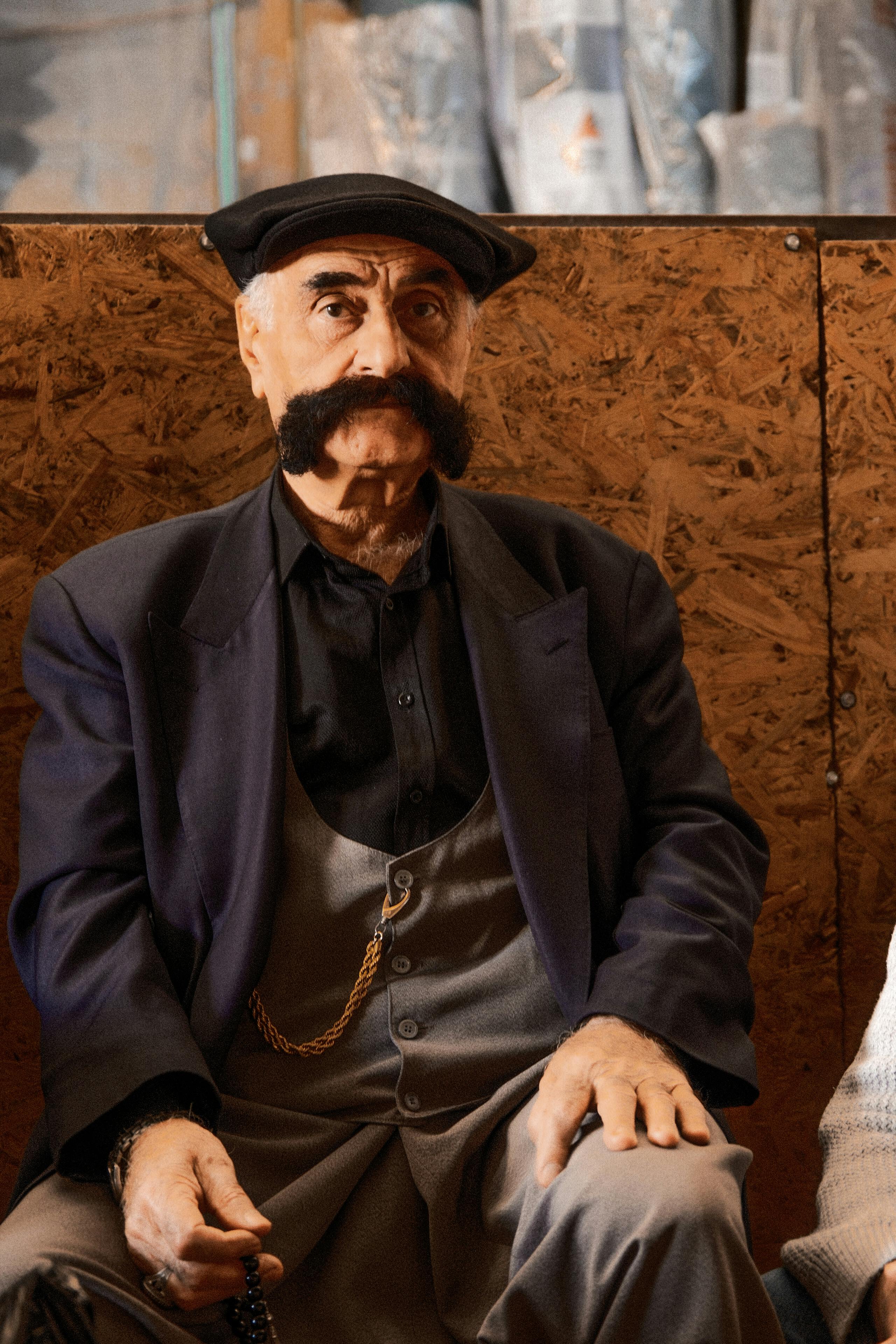 Captivating portrait of a senior man sporting a unique thick mustache, seated indoors.