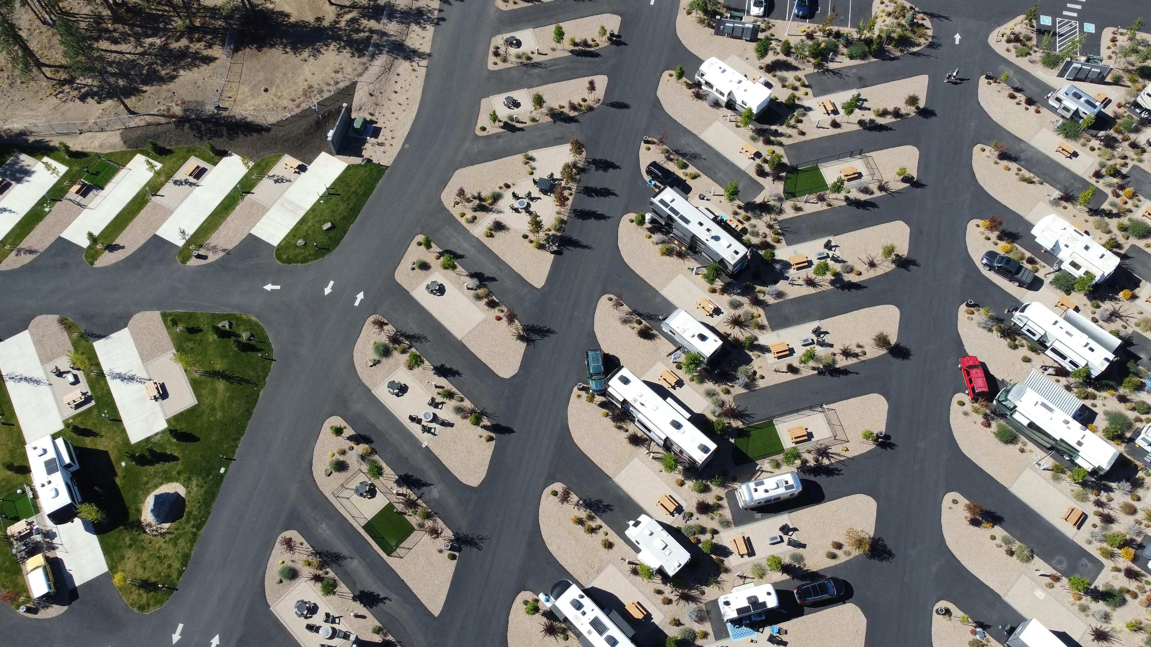 Aerial shot of a modern RV park layout with parked vehicles and paved paths.