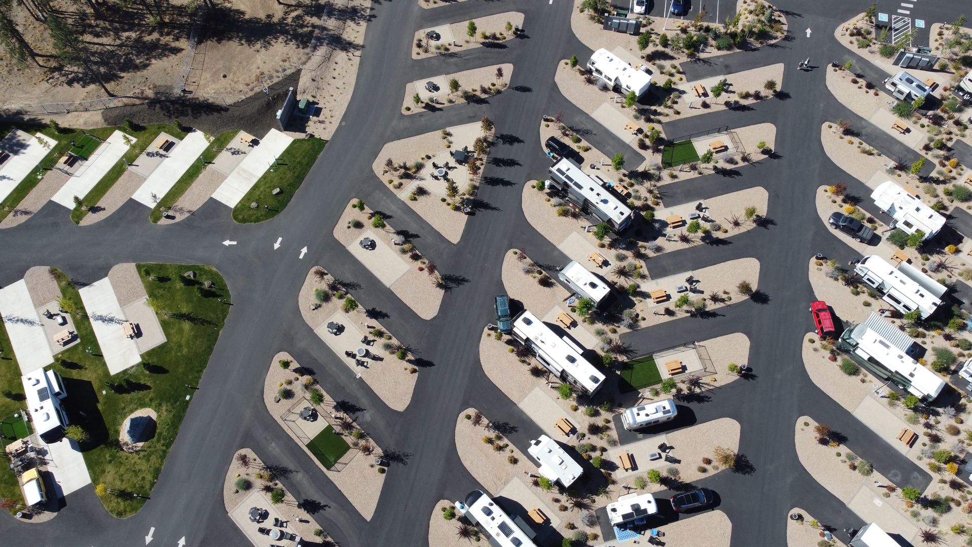 Aerial shot of a modern RV park layout with parked vehicles and paved paths.