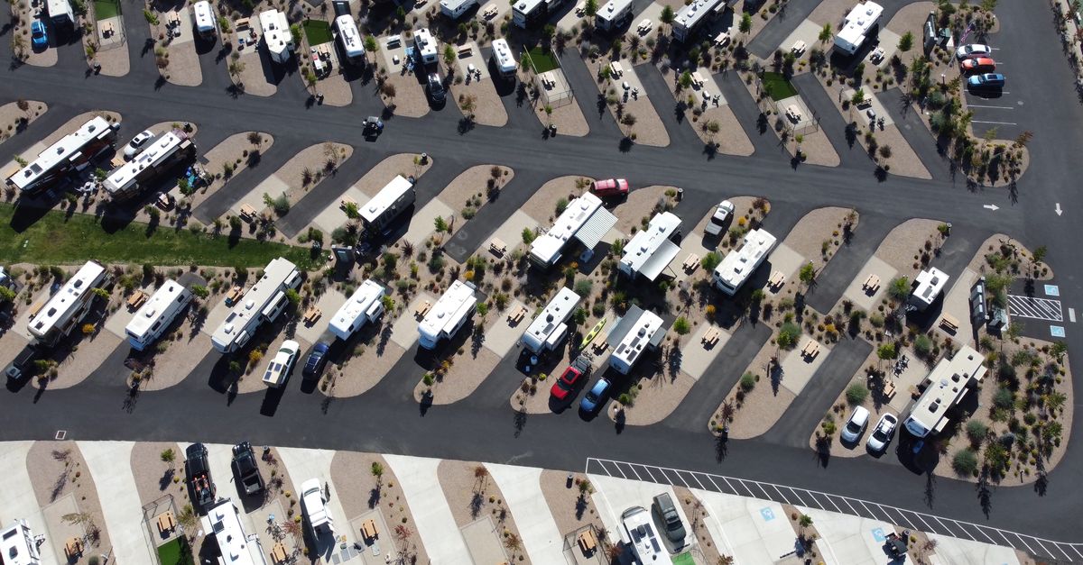 Aerial view of a spacious RV park with several campers and vehicles in designated spaces.