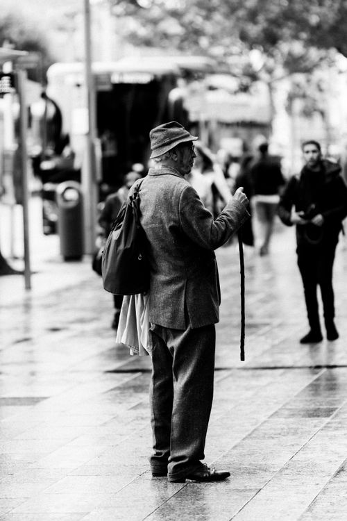 Free Black and white photo of an elderly man with a cane on a rainy day in Dublin, Ireland's bustling streets. Stock Photo