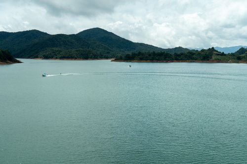 Free Scenic view of boats on Guatapé Reservoir surrounded by lush hills under a cloudy sky. Stock Photo