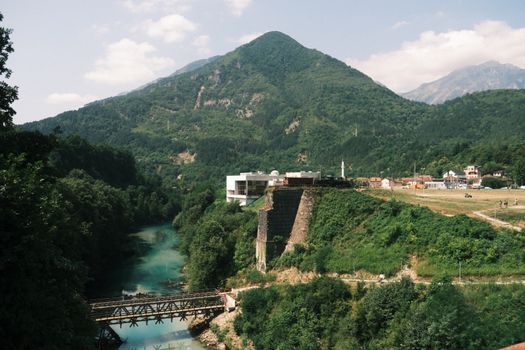 A tranquil riverside view with lush greenery and mountains in Bosnia and Herzegovina.