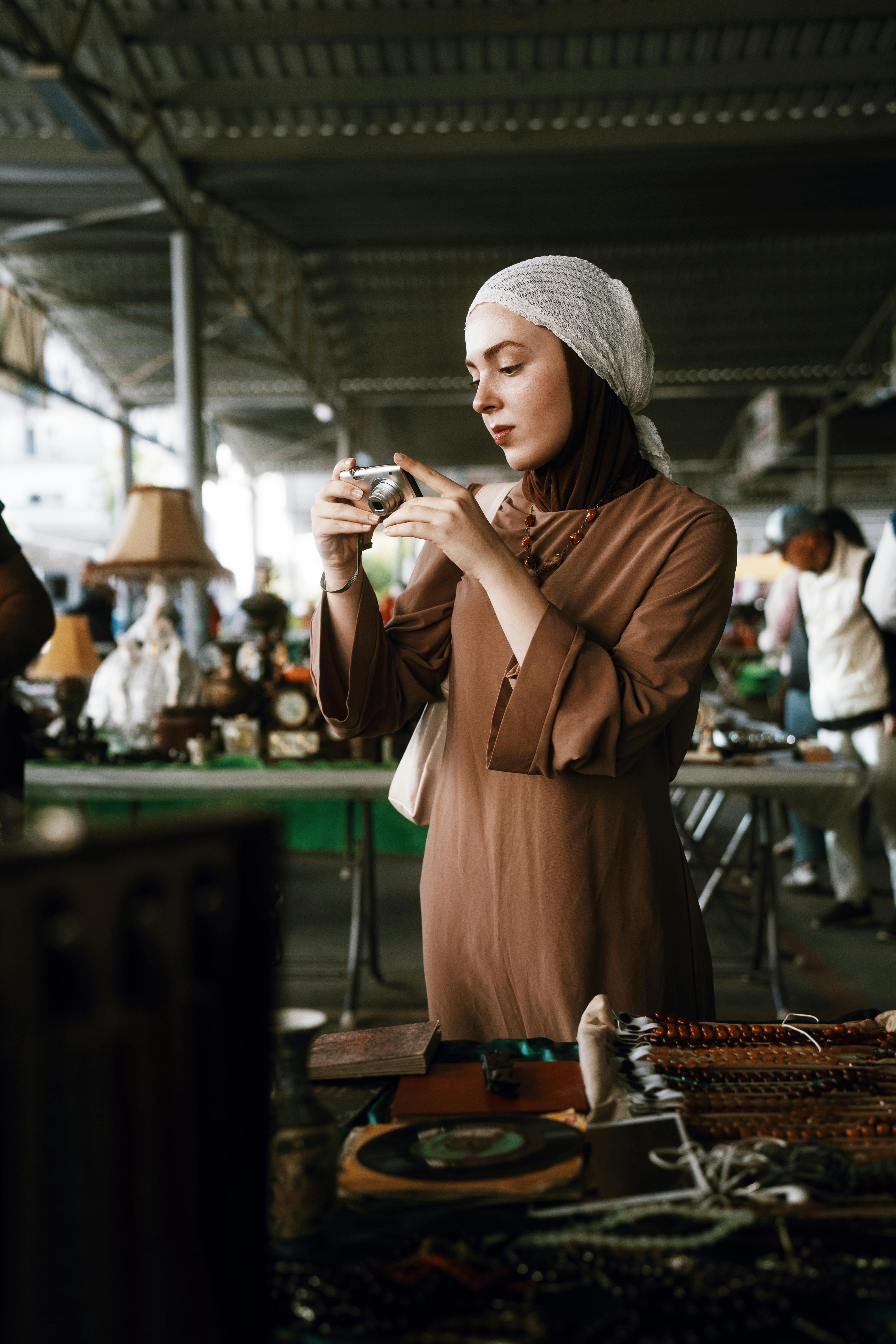 A woman inspects a vintage camera at an Antalya antiques market, showcasing cultural interest and fashion.