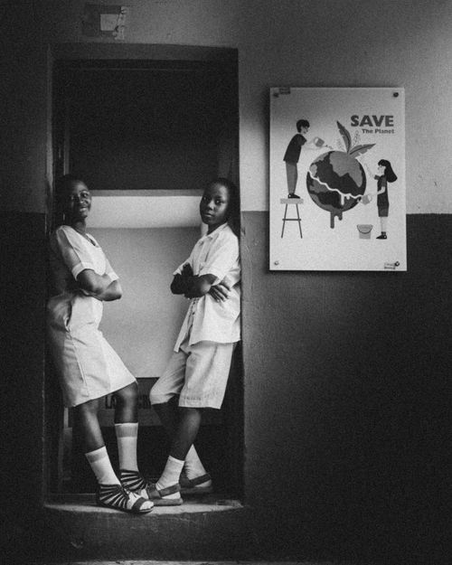Free Two students pose in school setting next to 'Save the Planet' poster. Stock Photo