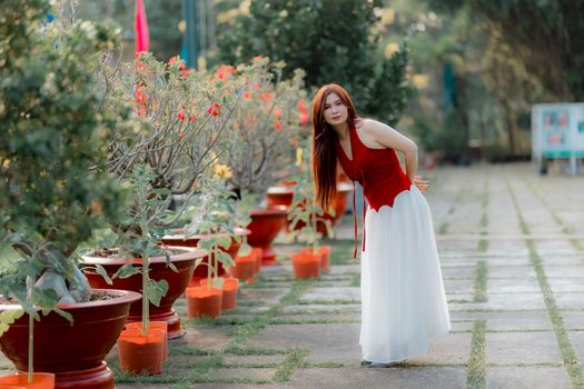 Elegant woman in a vibrant garden, embracing nature's beauty.