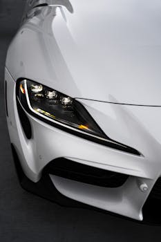 Detailed close-up of a sleek white sports car's headlight showcasing modern design.