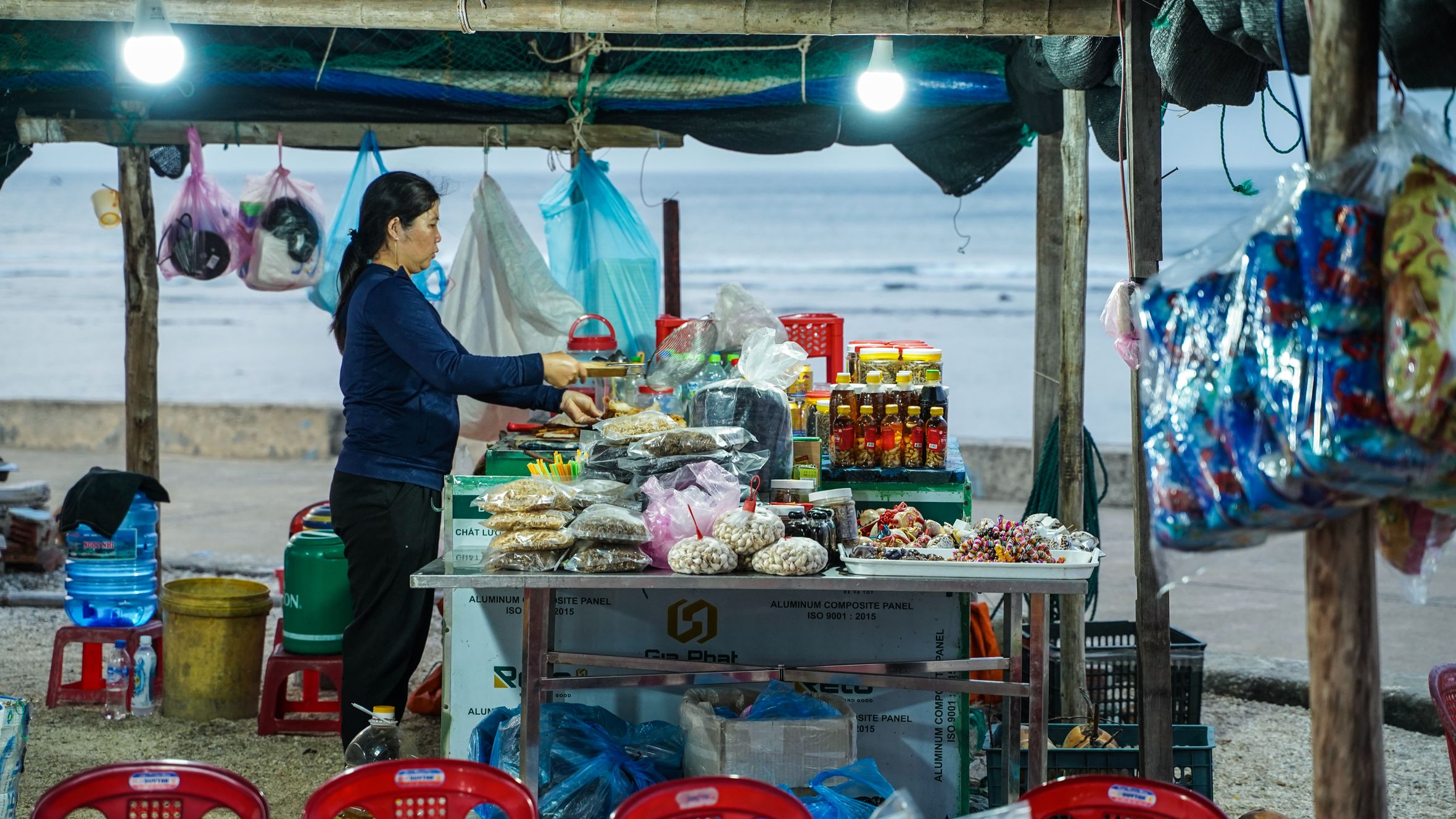 A local vendor woman sells goods at an outdoor coastal market stall in Ly Son.