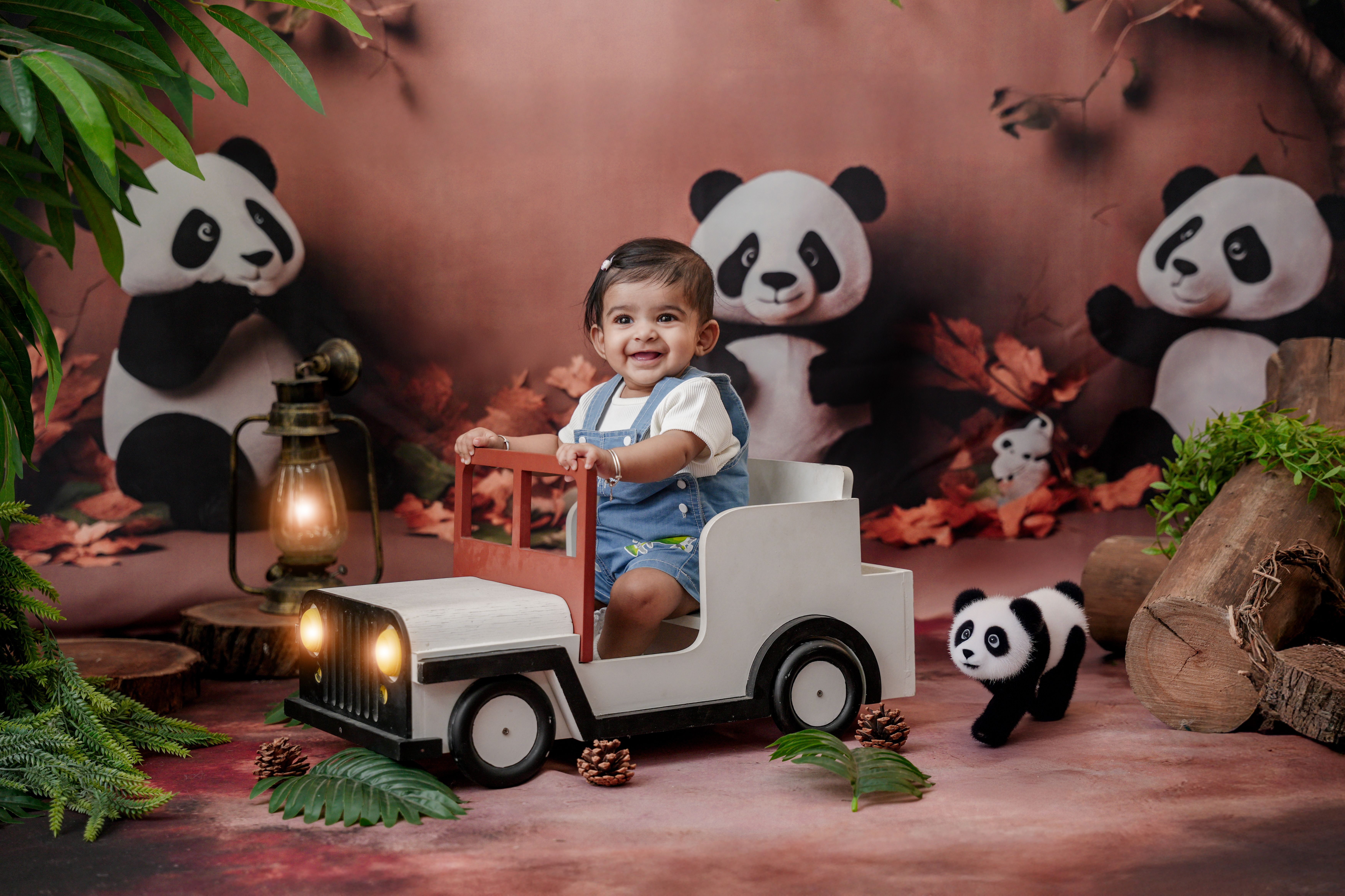 Charming scene of happy baby in toy car surrounded by playful panda decor.