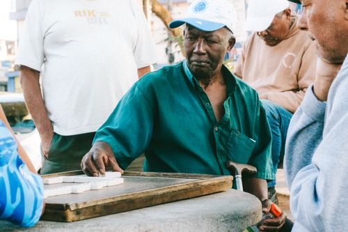 Free Elderly men engaging in a friendly game of dominoes on a São Paulo street corner, capturing local culture and tradition. Stock Photo