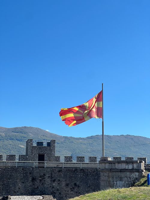 Free North Macedonian flag waves atop an ancient fortress under clear blue skies. Stock Photo