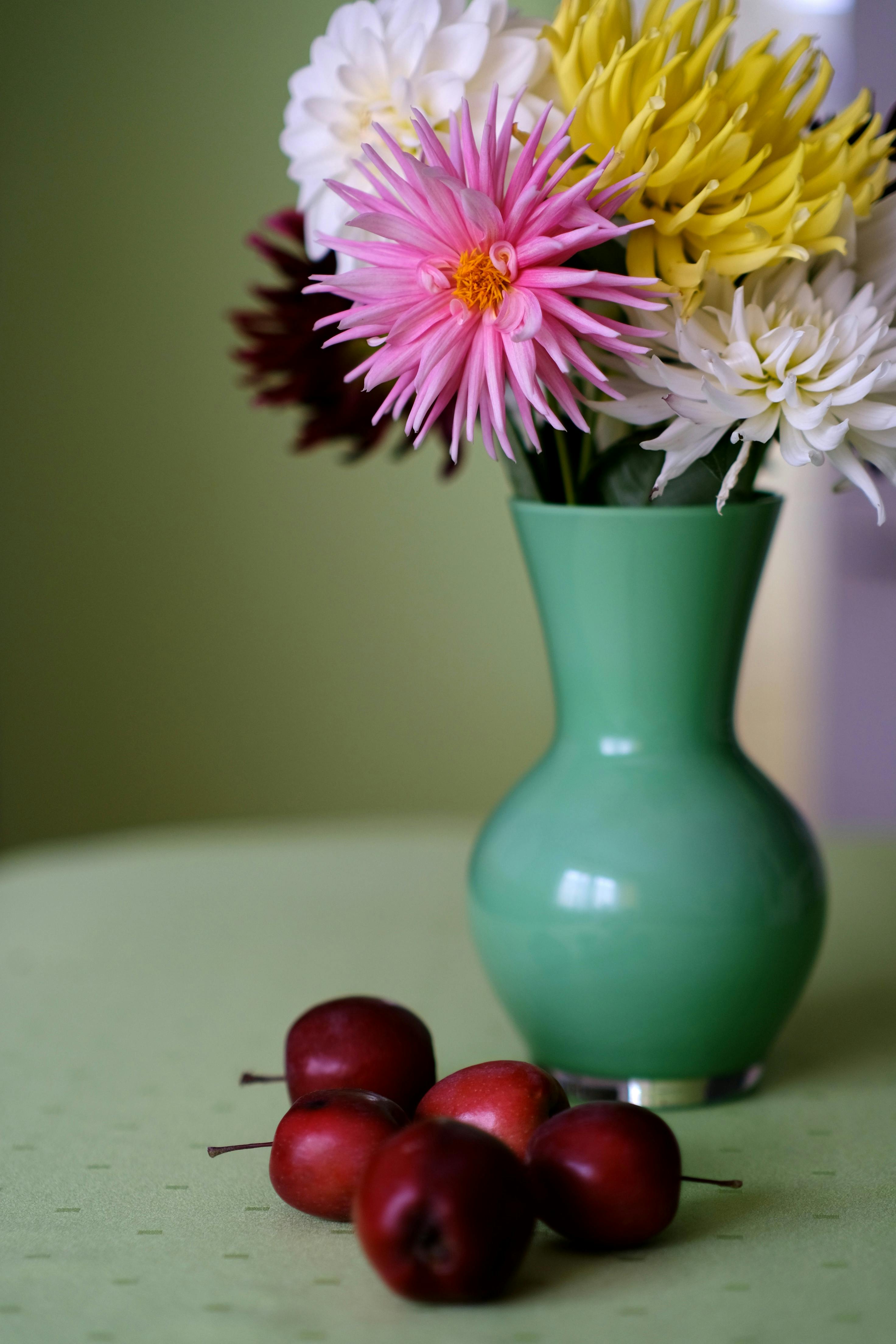 [ColoSach]-a-colorful-floral-arrangement-in-a-green-vase-beside-fresh-red-crabapples-on-a-table.