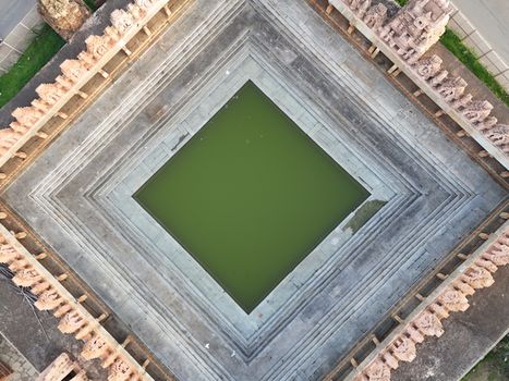 A top-down view of a symmetrical architectural structure with a green water pool.