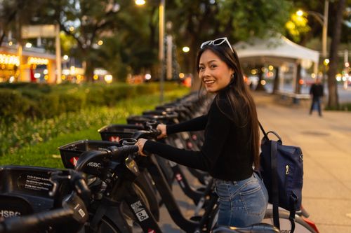 Free Smiling woman rents bike in vibrant Mexico City during evening. Stock Photo