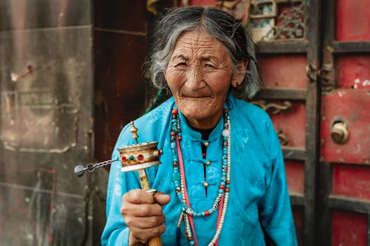 Portrait of an elderly Tibetan woman holding a prayer wheel in Garzê, Sichuan, China.