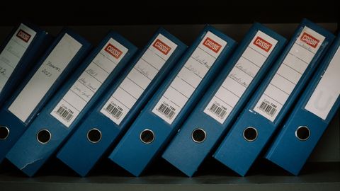 Neatly arranged blue office binders labeled with dates and names for organized storage.