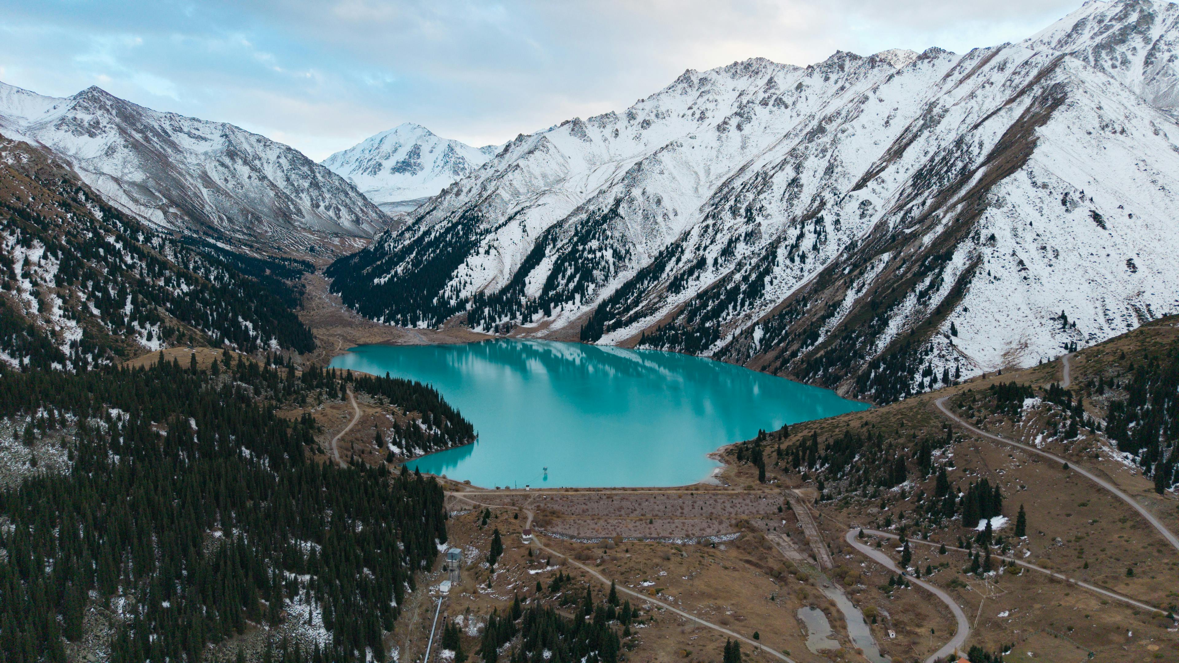 Scenic aerial view of Big Almaty Lake surrounded by snowcapped mountains in Kazakhstan.
