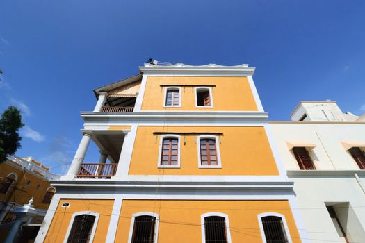 Vibrant yellow colonial building with tall columns under a bright blue sky, showcasing classic architectural style.