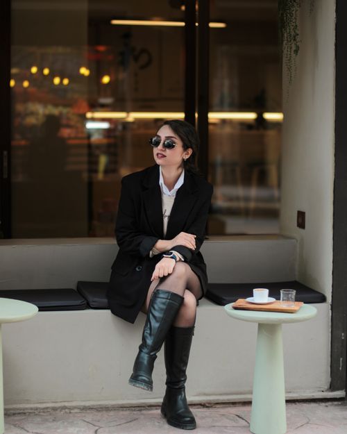 Free Fashionable woman in a chic black outfit sitting at a trendy outdoor cafe. Stock Photo