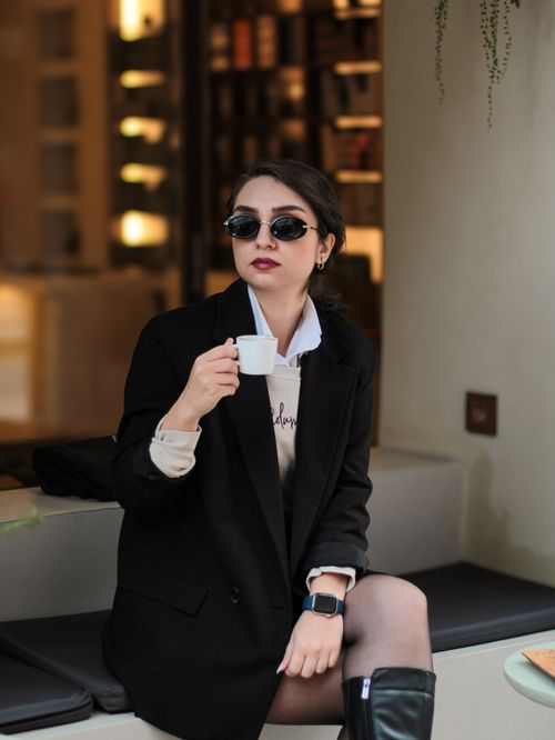 Free Fashionable woman in sunglasses sipping espresso indoors, exuding elegance and style. Stock Photo