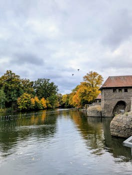 Autumn river scene with colorful foliage and historic building in Leipzig.