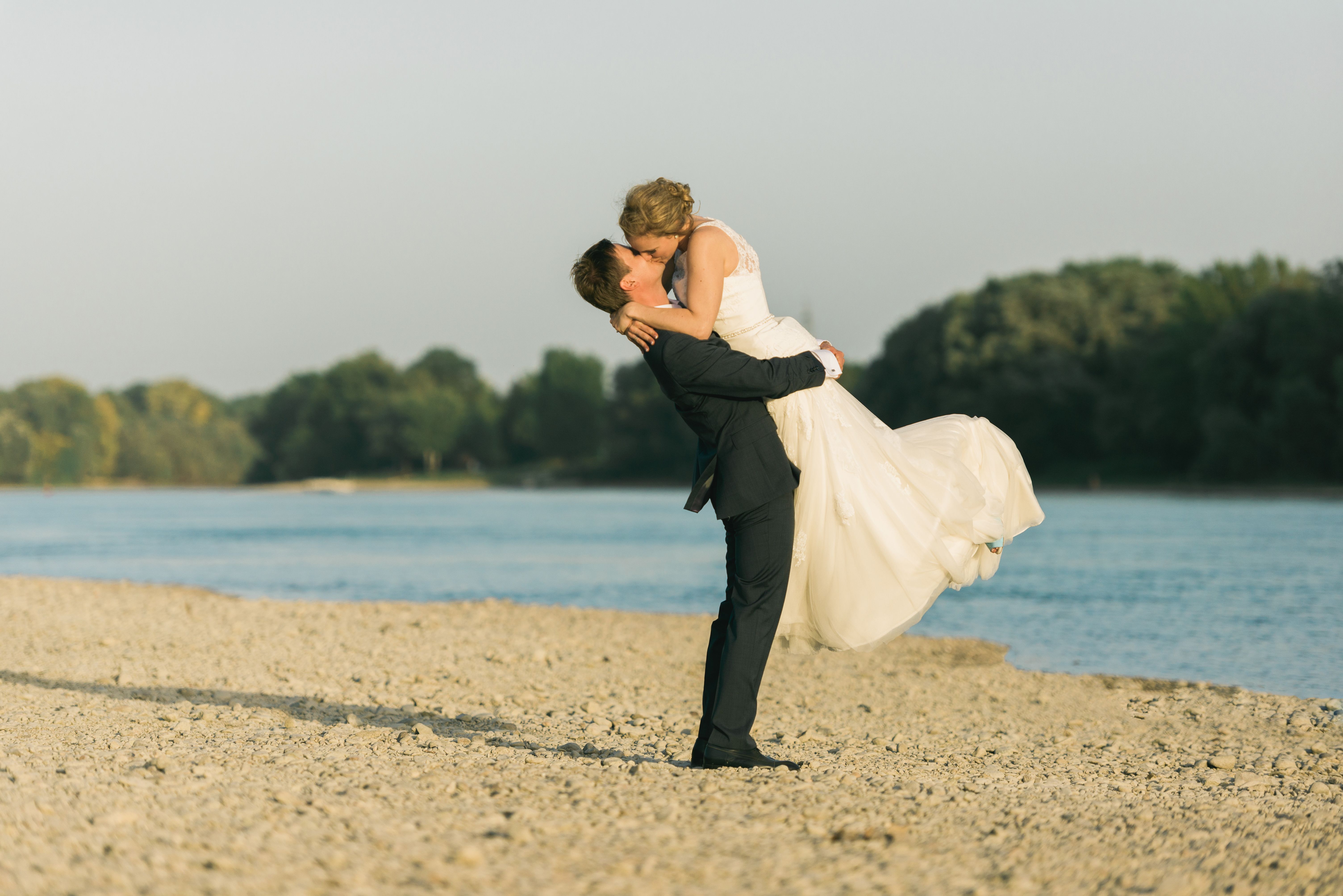 Bride and groom embracing joyfully on a scenic beach, celebrating their wedding.