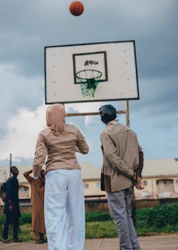 Group of people playing basketball outdoors on a cloudy day.