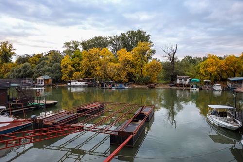 Free Calm river with boats and vibrant autumn trees reflecting in the water. Stock Photo