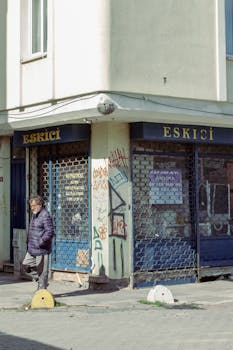Street scene showing a man walking past a graffiti-covered building in daylight.