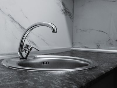 Stainless steel kitchen sink and faucet with marble backsplash