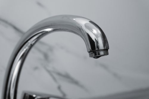 Free Close-up of a chrome faucet with a marble background, highlighting modern interior design. Stock Photo
