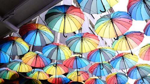 Free Colorful umbrellas create a vibrant canopy in a city setting, adding life to the urban scene. Stock Photo