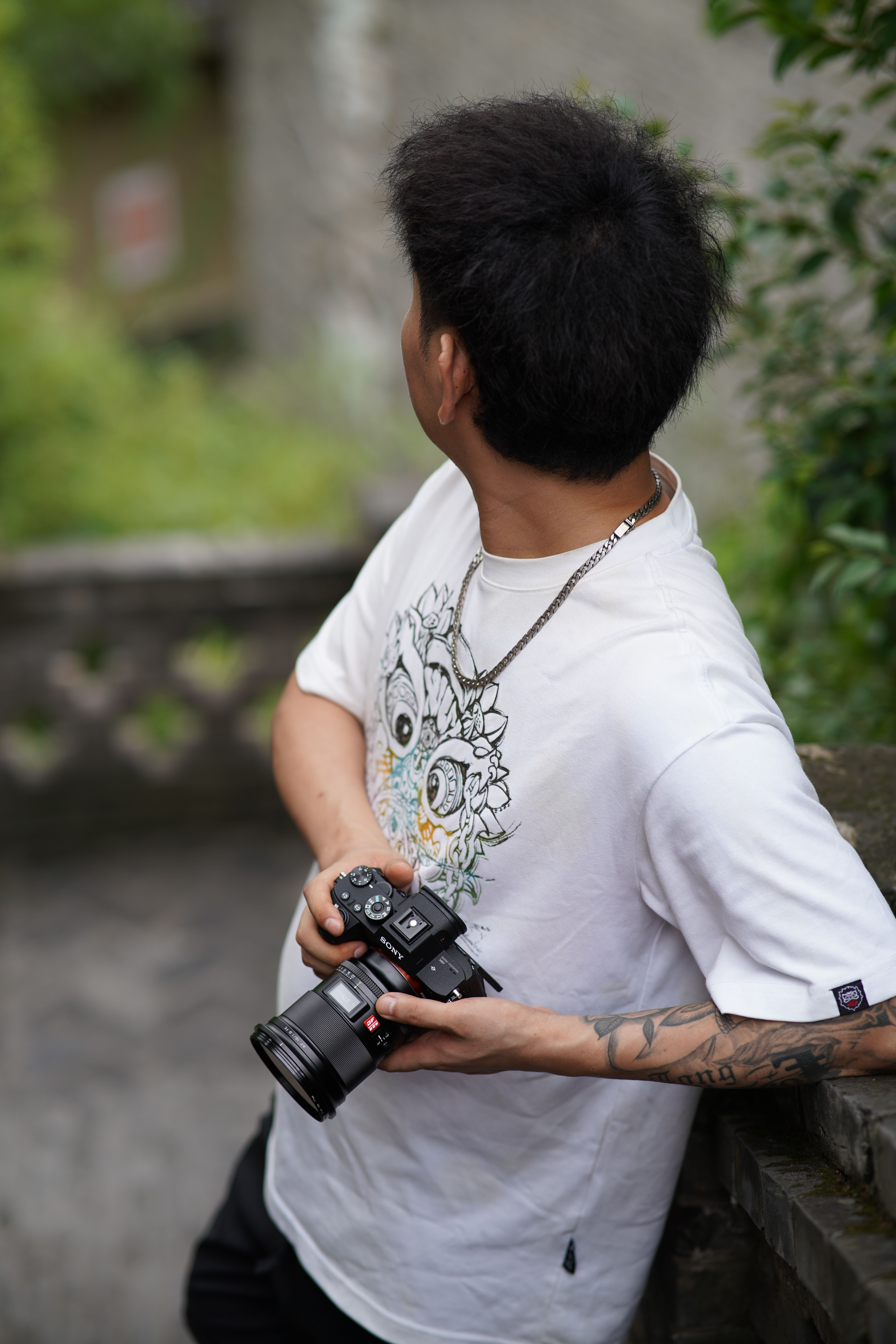 A travel photographer stands outdoors, holding a camera, ready to capture scenic views.