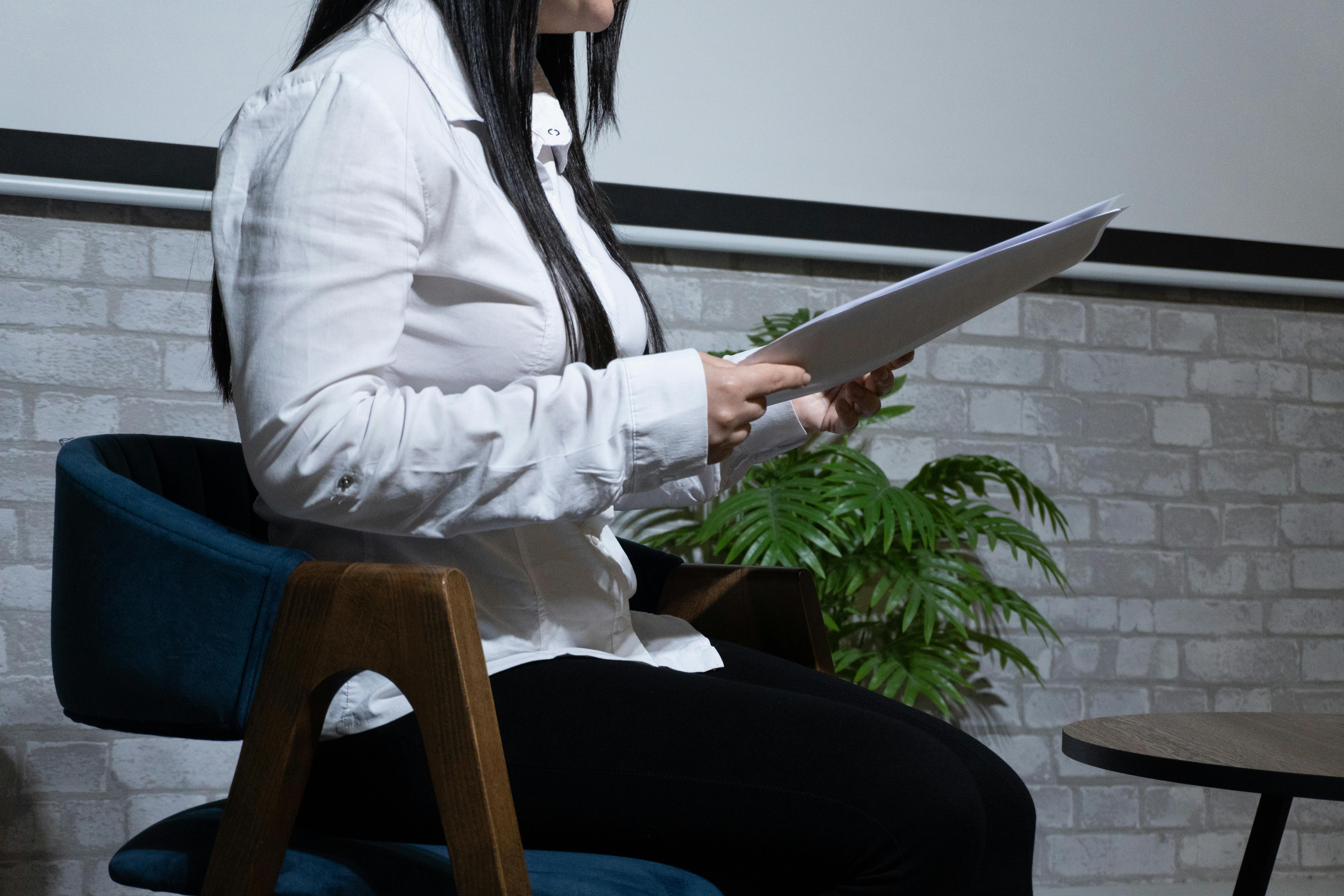 Gratis Mujer de negocios en una oficina moderna sosteniendo documentos y leyendo atentamente. Foto de stock