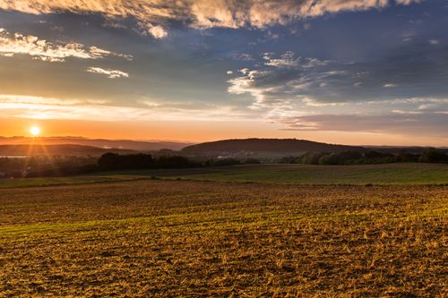 Free Beautiful sunset over expansive countryside fields, capturing the serene evening sky. Stock Photo
