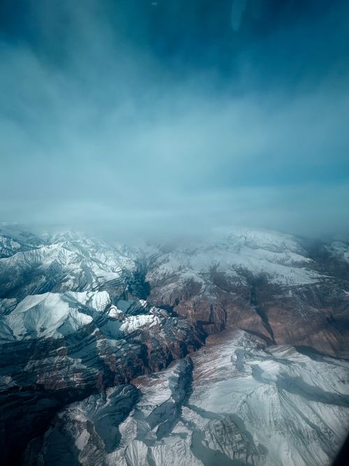 Free Spectacular aerial view of snow-covered mountains beneath a vast, blue sky. Stock Photo