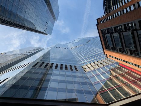 Modern skyscrapers reaching towards a clear blue sky, captured in an urban setting from a low angle.