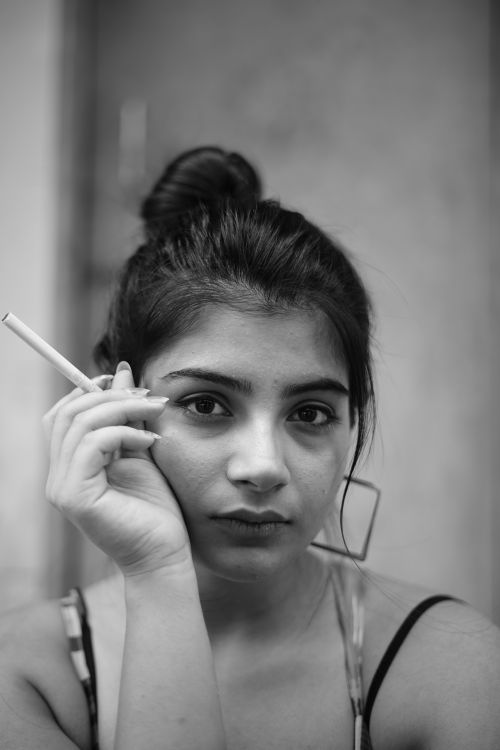 Free Black and white portrait of a thoughtful woman holding a cigarette, showcasing introspective beauty. Stock Photo