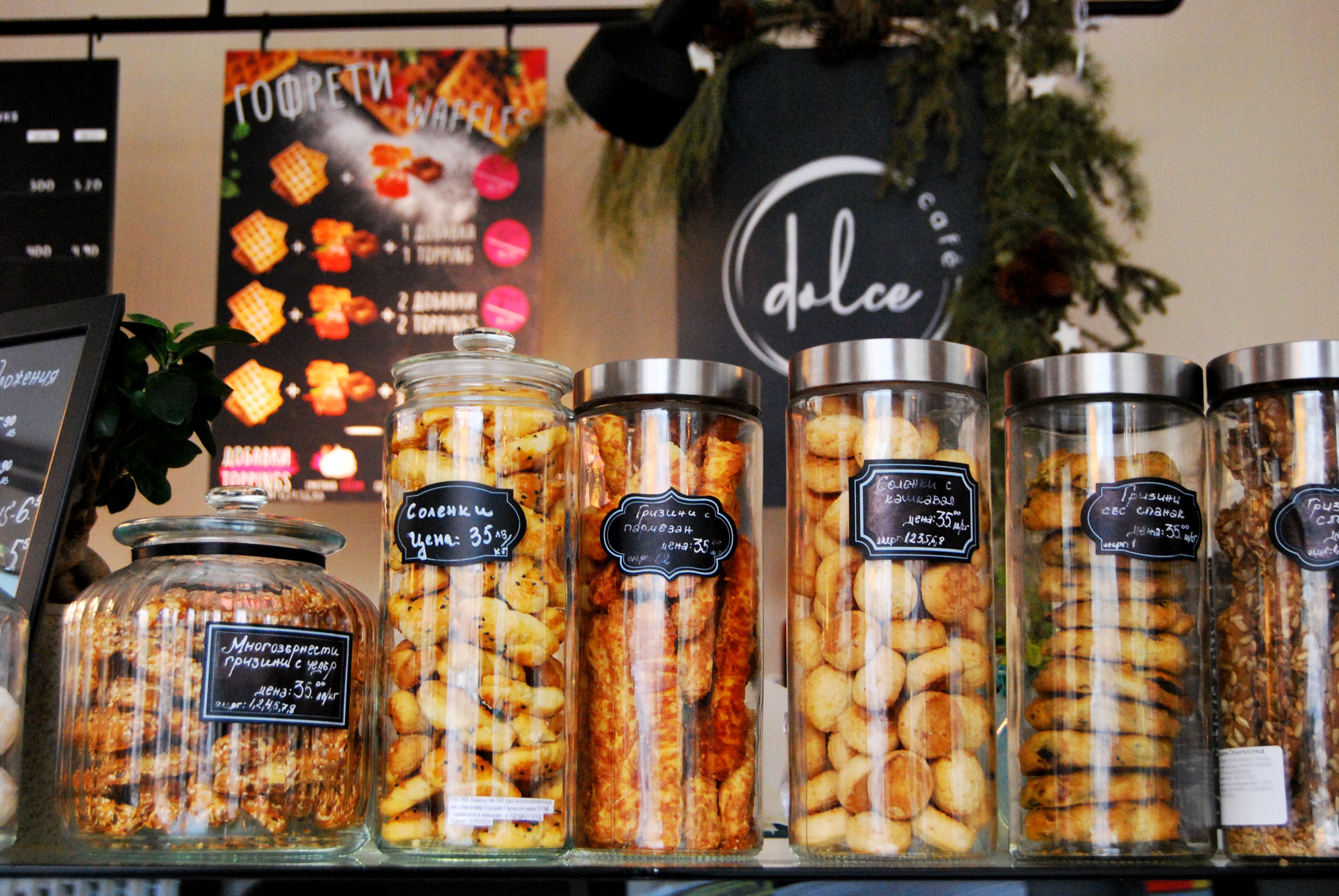 Assorted biscuits displayed in glass jars on a cafe counter, showcasing an array of textures and flavors.