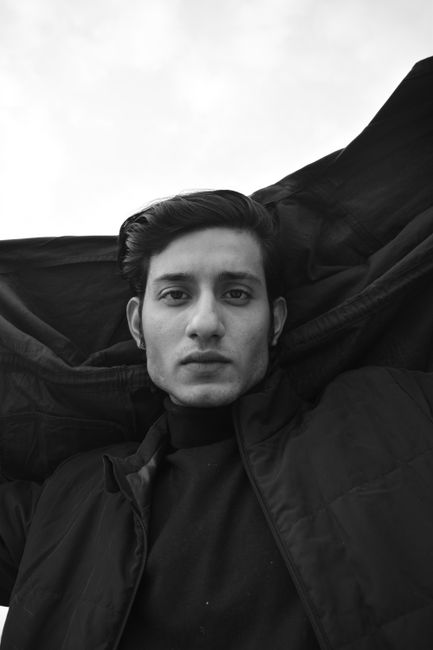 Black and white portrait of a man with a serious expression wearing a black jacket.