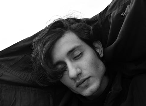 A peaceful black and white headshot of a young man with eyes closed, exuding calmness.