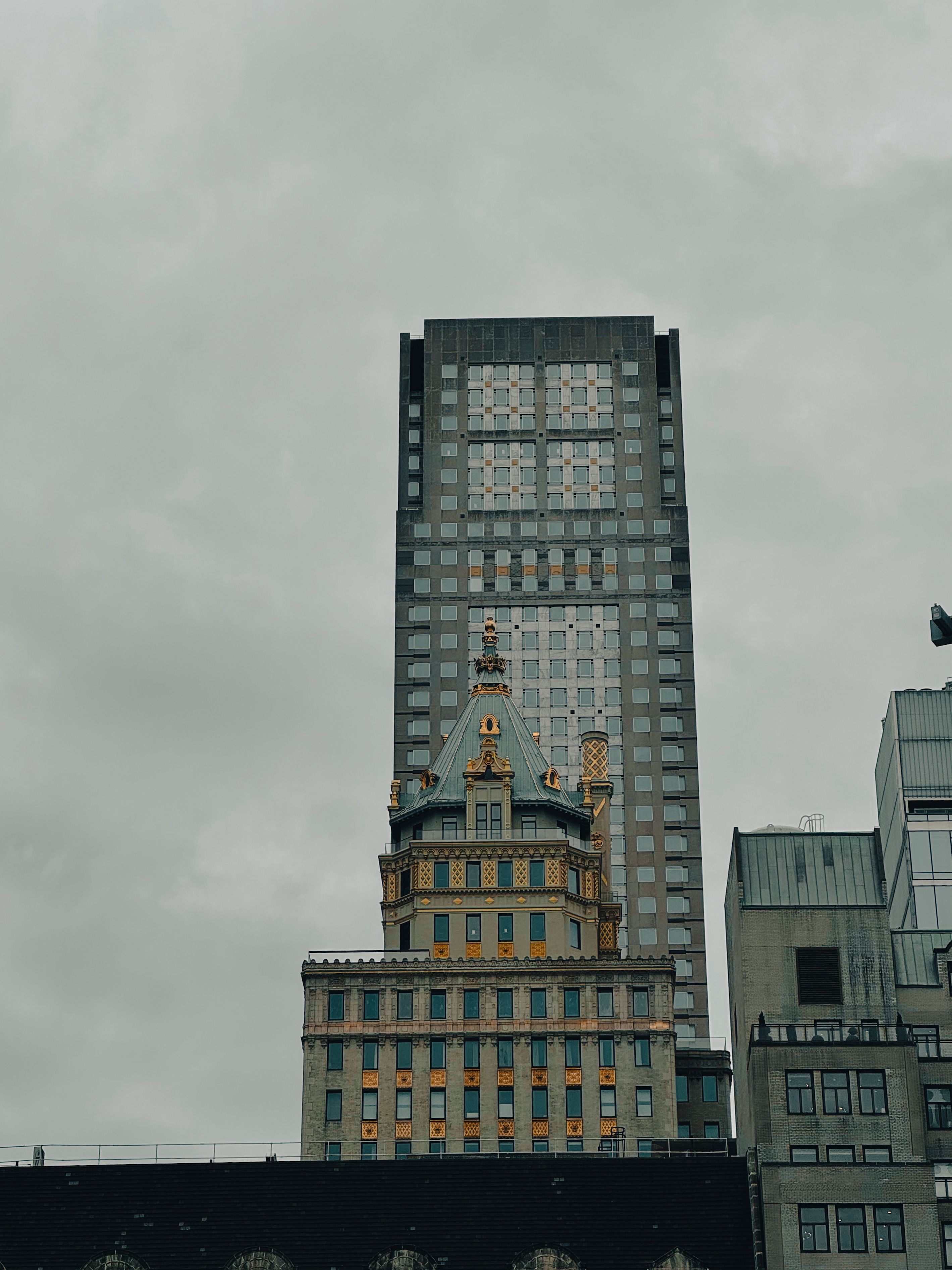 A striking blend of historic and modern architecture in New York City under a cloudy sky.