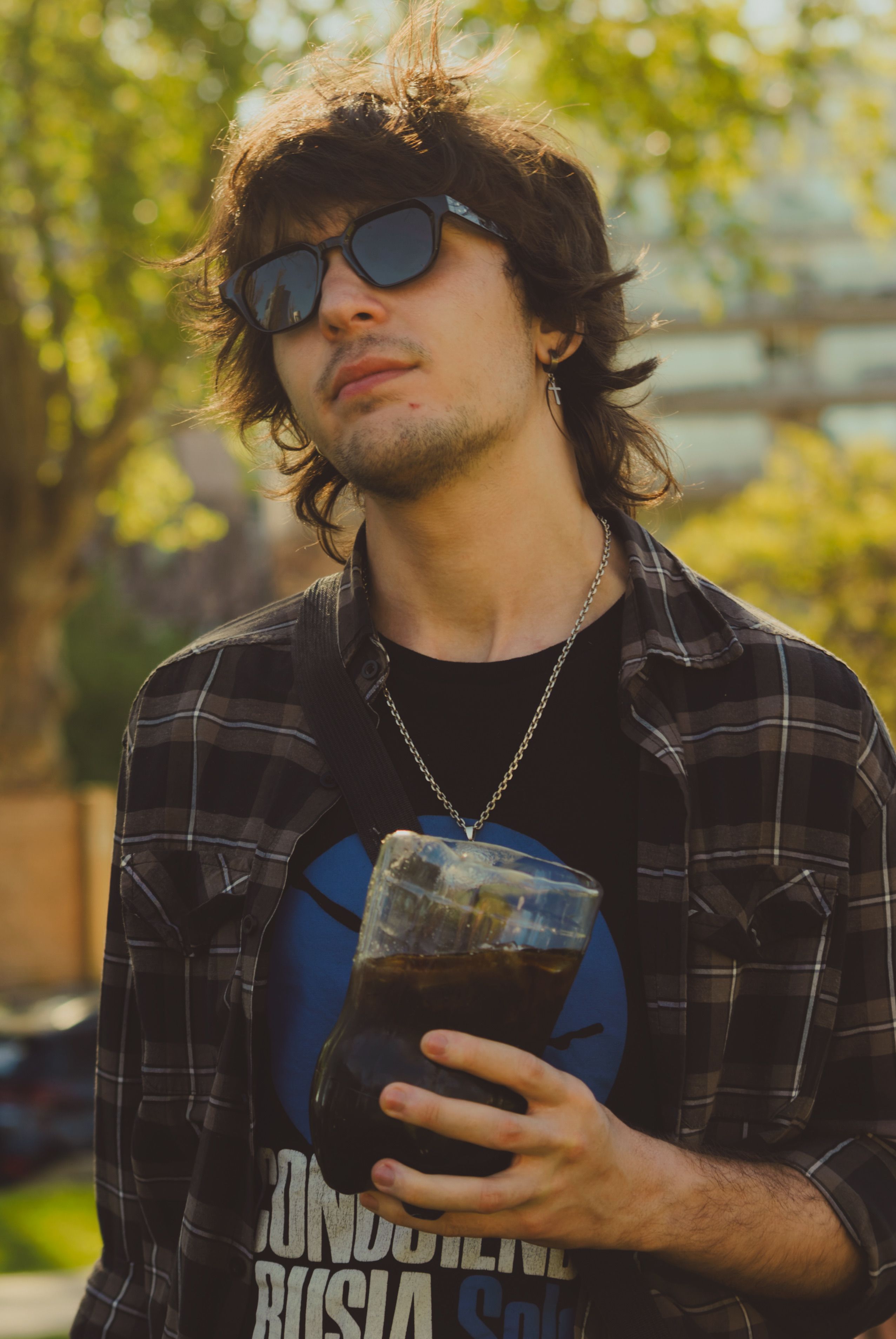 A stylish young man enjoys a drink in a Buenos Aires park, capturing the city's vibrant atmosphere.