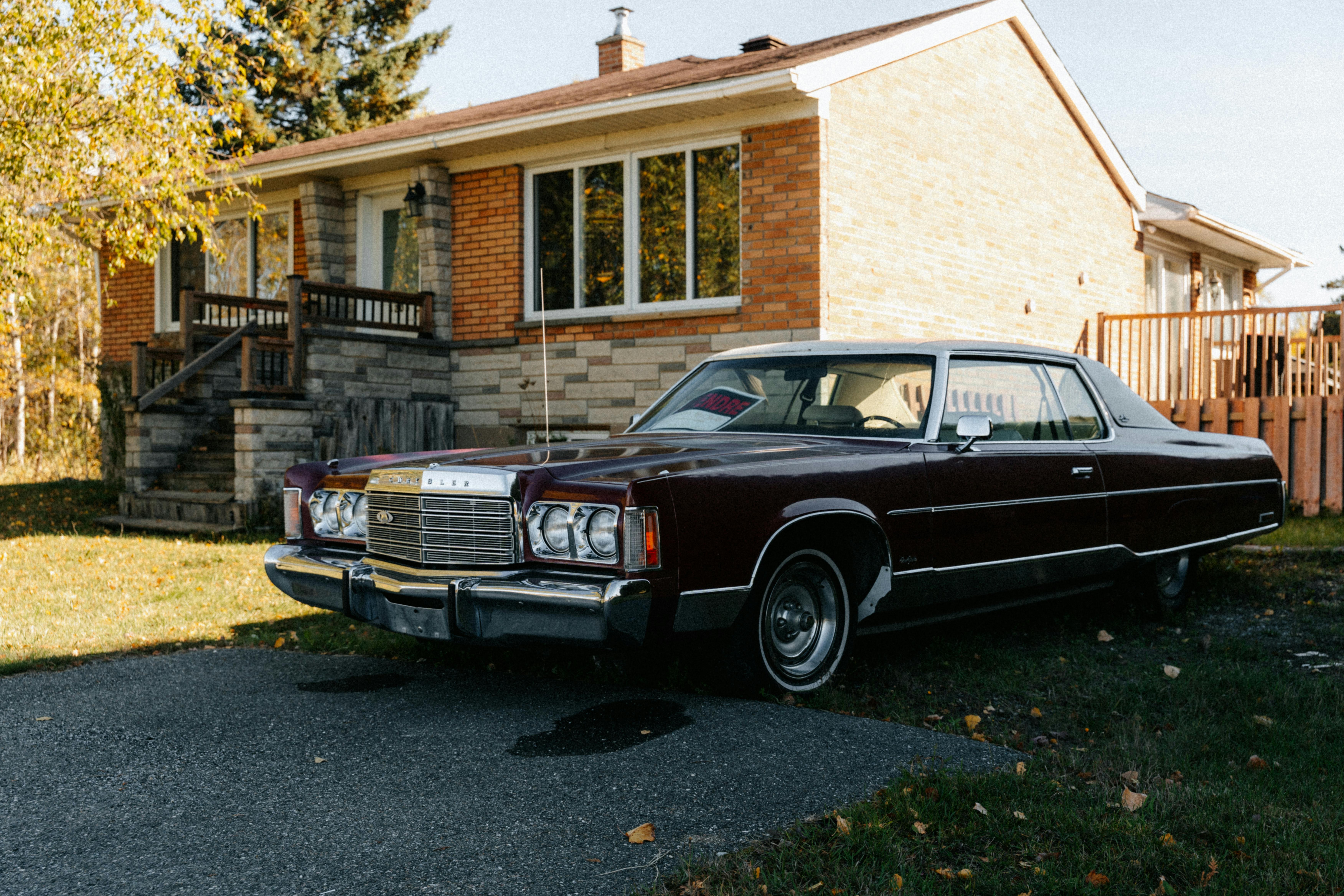 Classic vintage car parked in front of a brick house during autumn in North Hatley, Qu&eacute;bec.