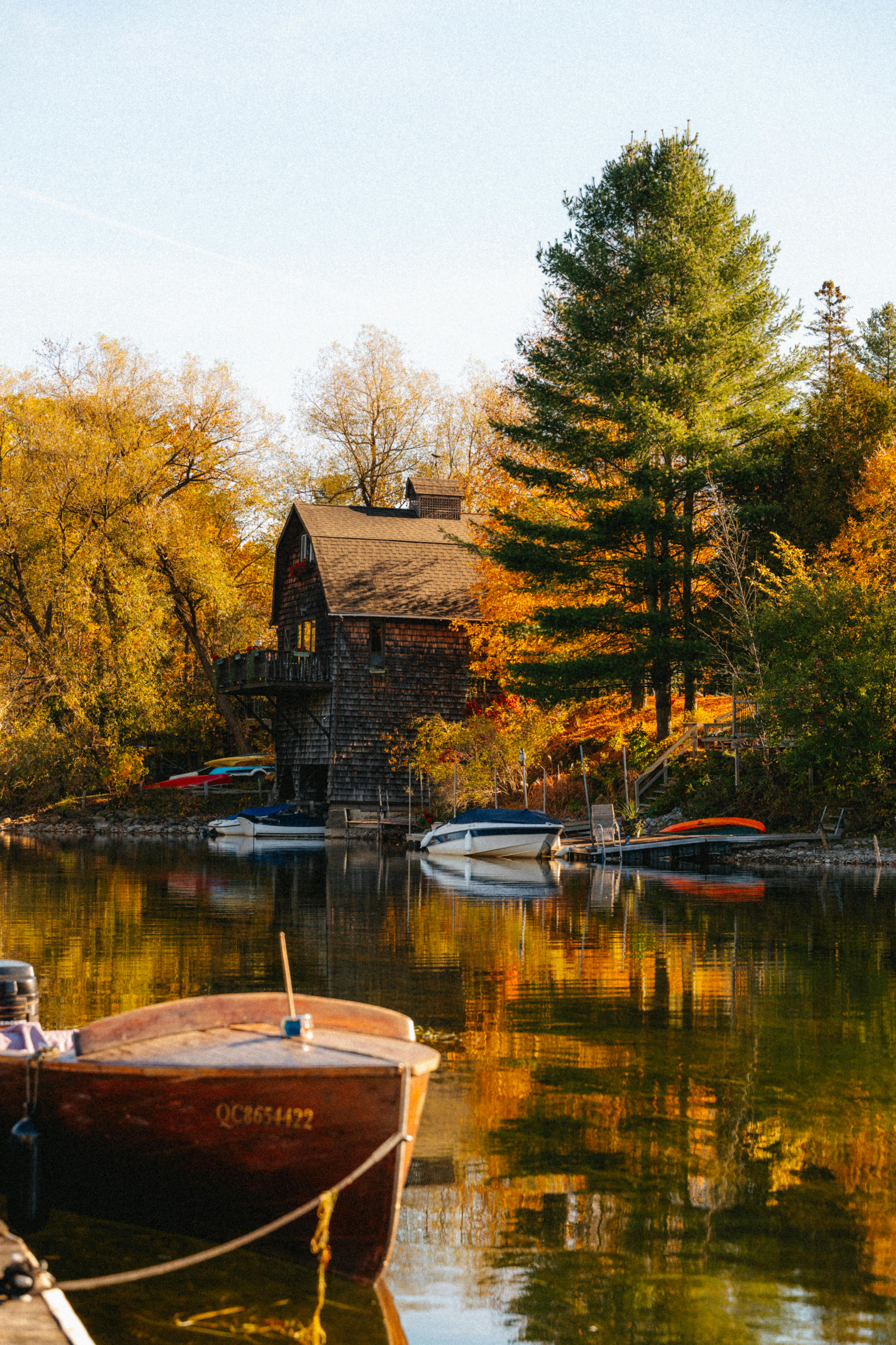 Idyllic lakeside cottage surrounded by vibrant fall foliage in North Hatley, Québec.