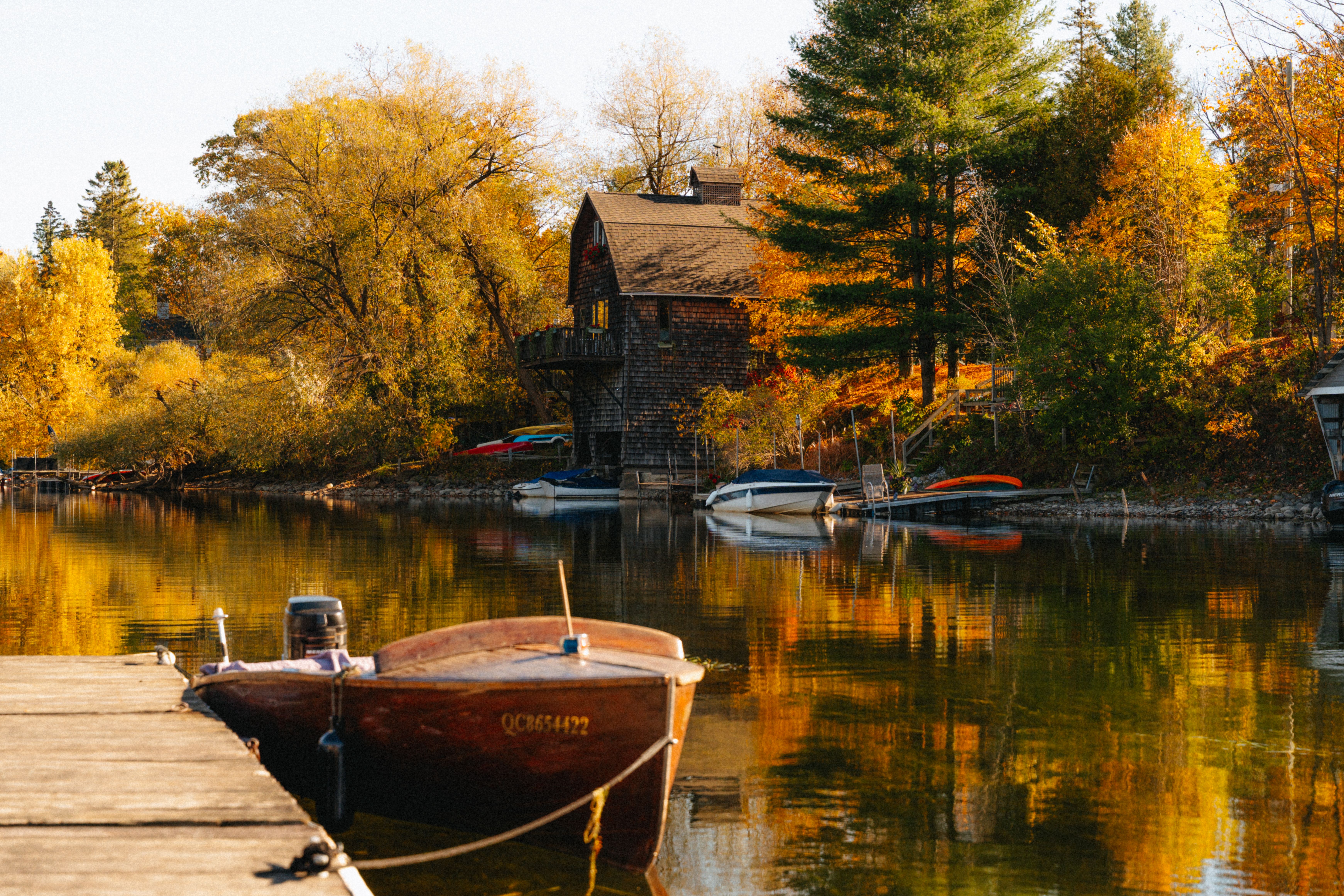 Picturesque autumn scene with a house and boats on a lake in North Hatley, Québec.