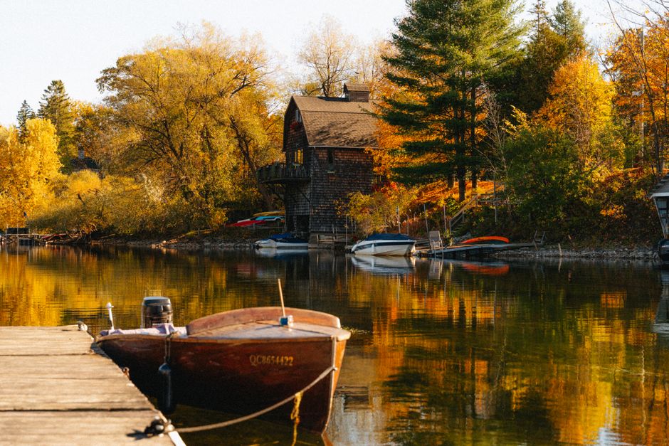 Picturesque autumn scene with a house and boats on a lake in North Hatley, Québec.