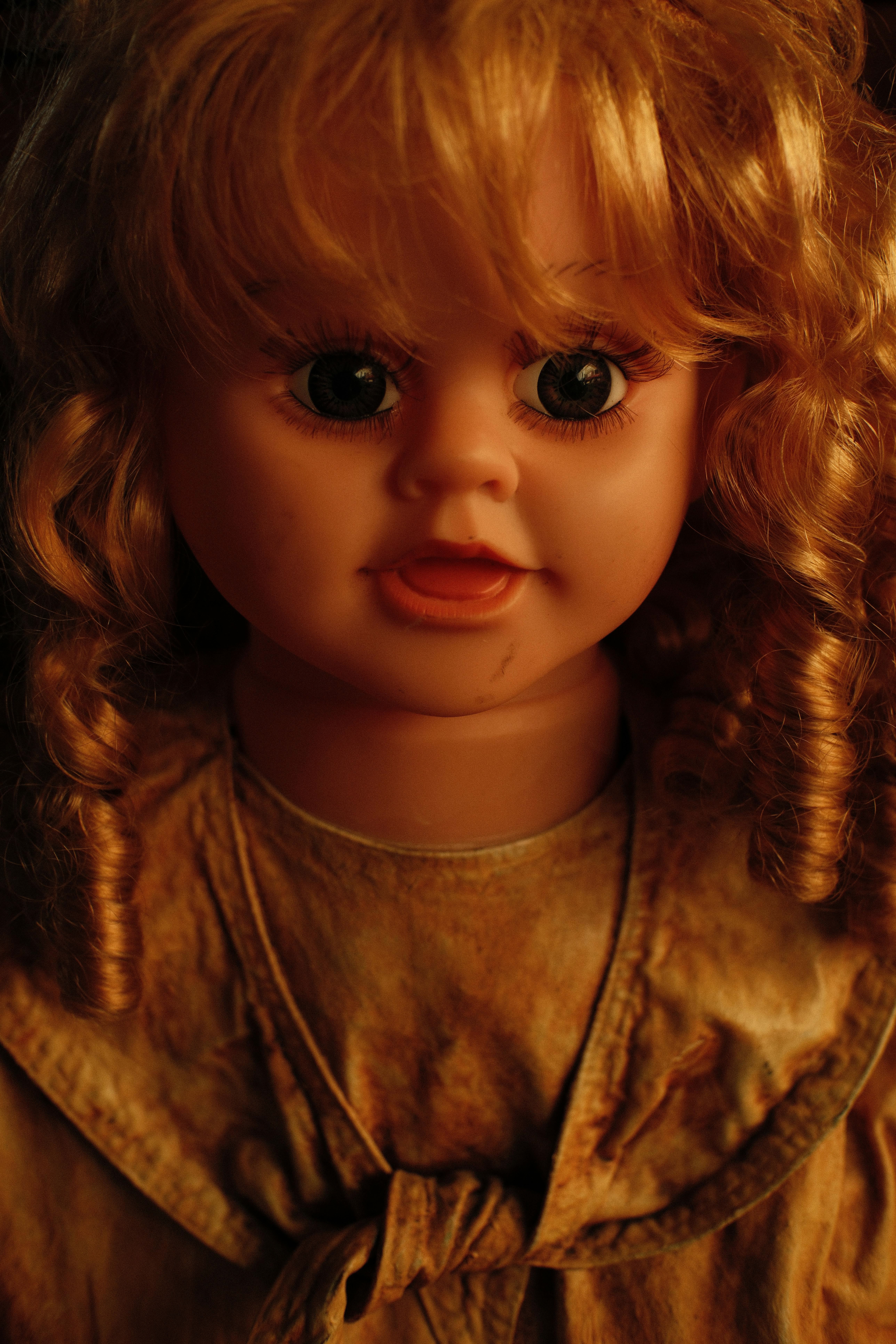 Vintage doll featuring curly hair with warm lighting creating an eerie ambiance.