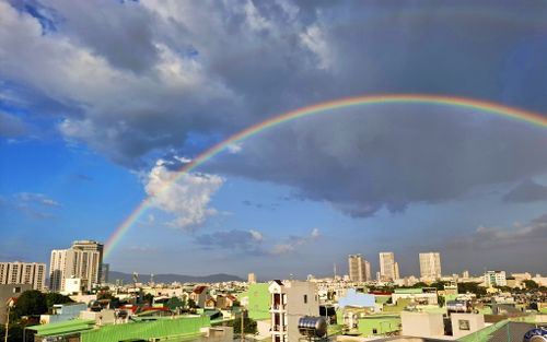Free A vibrant rainbow spans across a cityscape under dramatic clouds, showcasing an awe-inspiring urban nature view. Stock Photo
