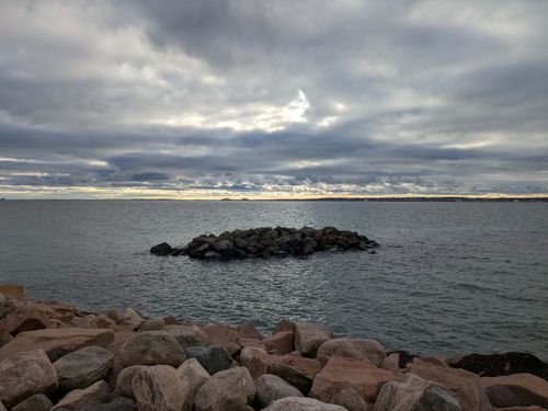 Free Serene rocky coastline with a cloudy sky and soft daylight, perfect for tranquility themes. Stock Photo